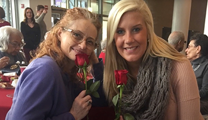 Female buddy and mentor pose for photo, holding roses