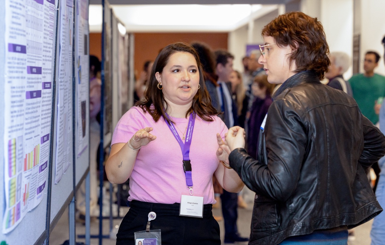Allegra Kawles speaks to an attendee at the poster session